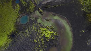 antenne dar visie shows zwart basalt, helder mos, en turkoois krater meren in IJsland. camera veegt bovengronds, onthullend gevlochten smelten kanalen en bezinksel pluimen. video