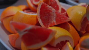 tajt makro visar röd grapefrukt kilar med gul skalar på en tallrik, en gaffel på de kant, värma Färg och grund djup av fält, mjuk naturlig ljus i malta video