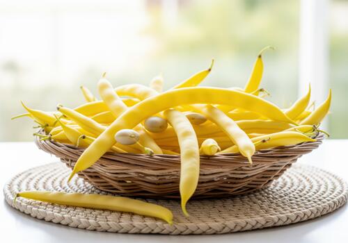 Fresh vibrant yellow wax beans piled high in a rustic wicker basket near a bright window photo