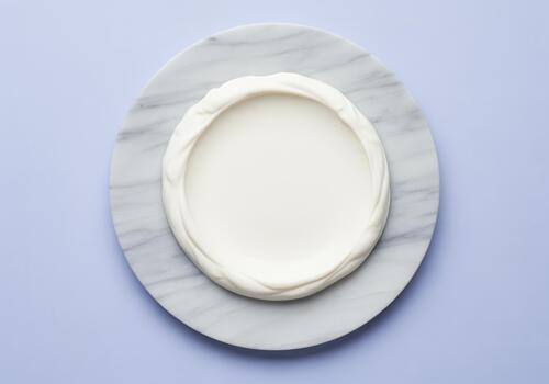 Perfectly smooth white cream texture on a round marble plate, clean top view. photo