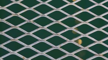 detaljerad stänga upp av en metall galler med diamant mönster över grön bakgrund, skapande engagerande texturer för arkitektonisk och design projekt video