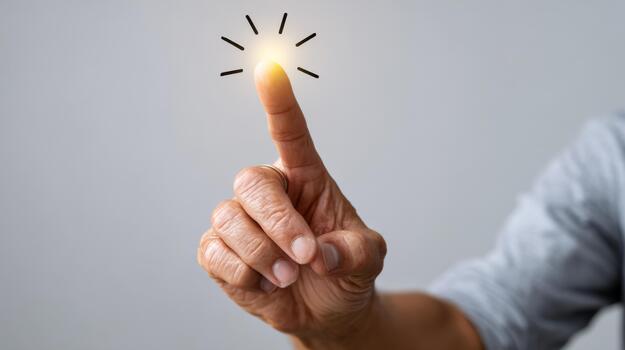A close-up of an elderly person's hand with a light glowing at the fingertip, symbolizing ideas and creativity. photo