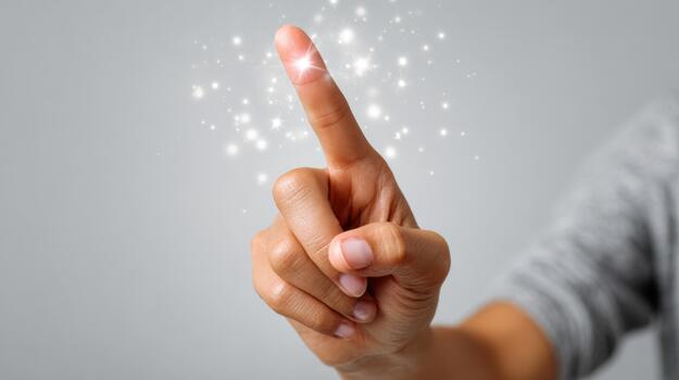 A close-up of a hand with a delicate touch, creating a sparkling effect, evoking magic and wonder in a light gray setting. photo