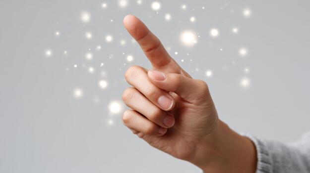 A close-up of a hand pointing upwards, surrounded by a magical glow of sparkling lights against a grey background. photo