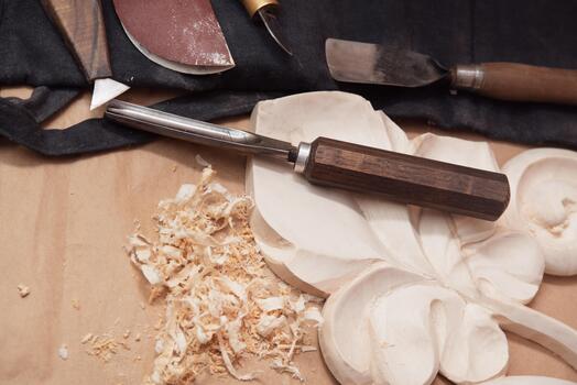 Tools for woodworking, artistic finishing lie on the table next to a decorative wooden element and shavings, top view, selective focus photo