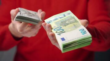 A man holds US dollars and euros in his hands and chooses which option is better video