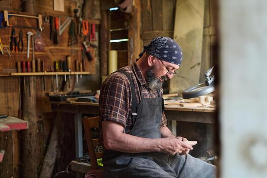 Craftsman working in his workshop, artisan shaping wood with hand tools, woodworking project, small business owner, hobbyist in rustic setting, creative process, skilled labor. photo