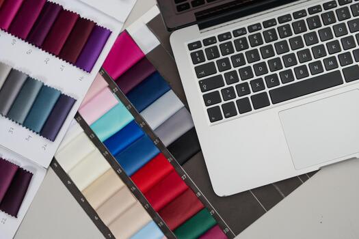 Laptop and fabric swatches, product photo of design process, material selection, and online ordering, studio shot with copy space minimal background, designer workspace