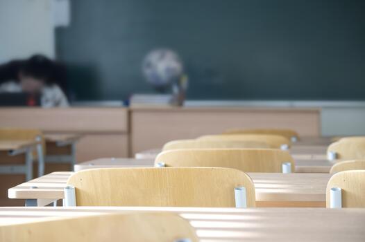 Inside an empty classroom with desks and chairs, with a chalkboard in the blurred background. photo