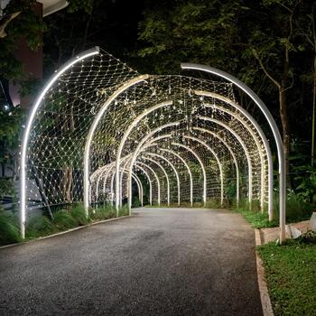 Curved white beams form an illuminated tunnel accented with hanging lights, and the structural lines create a clean pattern against the dark background.g photo