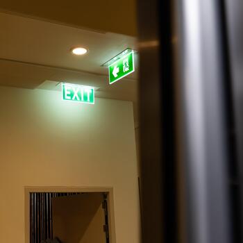 un verde fuego escapar firmar cuelga desde el techo, demostración un salida firmar verde ligero caja con un corriendo hombre y un flecha señalando Derecha para la seguridad y evacuación.e foto