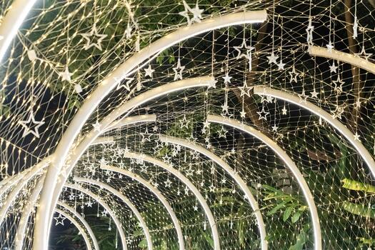 Curved white beams form an illuminated tunnel accented with hanging lights, and the structural lines create a clean pattern against the dark background.w photo