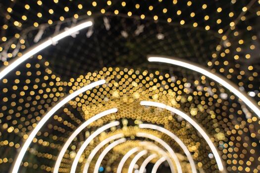Warm golden bokeh fills the frame with soft circles of unfocused light, while curved LED lines create a bright tunnel effect in the background.b photo