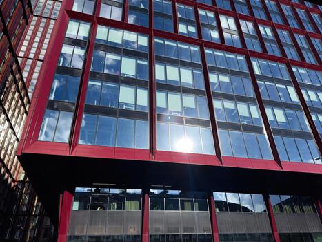 Manchester office building with red framed glass facade and reflective windows under bright sun photo