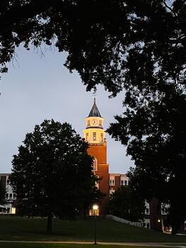 Clock tower Pulliam Hall on campus in Carbondale Illinois at dusk, framed by trees and warm lights photo