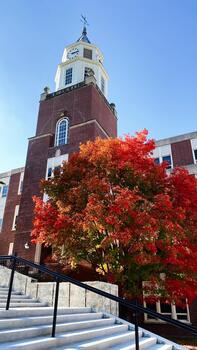 Clock tower on brick Pulliam Hall building with autumn maple tree in Carbondale Illinois campus photo