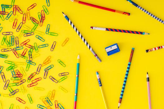 Colorful back to school composition with paper clips and coloured pencils on yellow background. Learning and creativity concept. Education and time idea. School aesthetic. Flat lay style. Top view. photo
