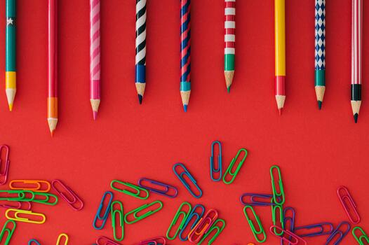 Colorful back to school composition with paper clips and coloured pencils on red background. Learning and creativity concept. Education and time idea. School aesthetic. Flat lay style. Top view. photo