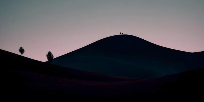 Two hikers are silhouetted on a majestic dark hill at twilight with subtle trees and a gradient sky creating a serene mood photo
