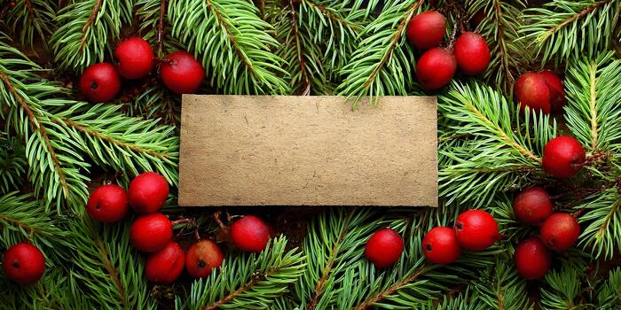 A brown rectangular card is surrounded by green pine tree branches and bright red berries creating a rustic holiday background photo