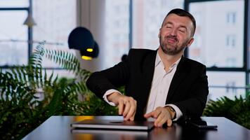 Smiling good-looking bearded man opens his laptop. Man changes in face when he can't open his computer. Blurred backdrop. video