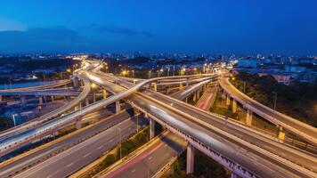 antenn se av en komplex motorväg utbyte på natt med stad lampor i de bakgrund på skymning video