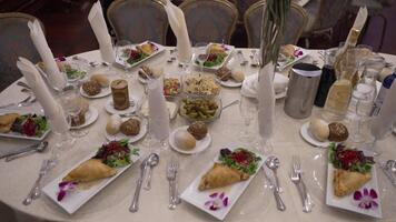ett elegant uppsättning bankett tabell för en jewish firande. funktioner aptitretare, sallader, och drycker, skapande en festlig, formell atmosfär. idealisk för händelse planera eller kulinariska innehåll. video