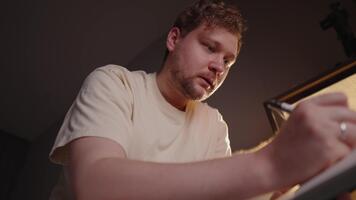 Frustrated artist struggling with creative block while drawing sketch at night, experiencing a creative crisis, illuminated by single lamp, various emotions from confusion to concentration video