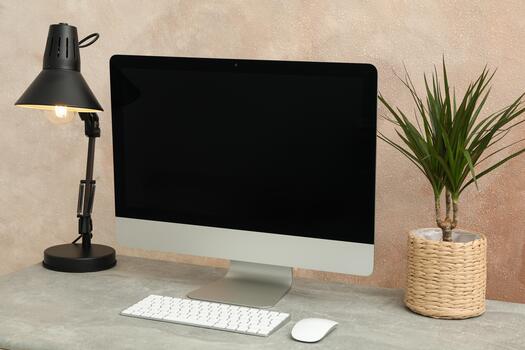 A computer monitor, keyboard and lamp on a desk photo