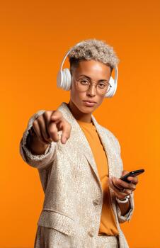 Confident non binary person pointing at camera with headphones photo