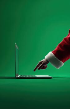 Santa hand pointing at laptop keyboard on green background photo
