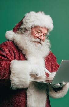 Santa Claus Pointing at Laptop Screen on Green Background photo