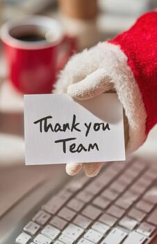 Gloved Santa Hand With Thank You Team Card at Keyboard photo