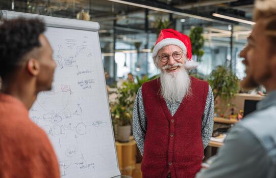 Senior santa style mentor smiling with team at flipchart photo