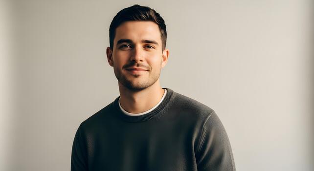 Portrait of a confident young man in a casual sweater smiling slightly with a beard photo