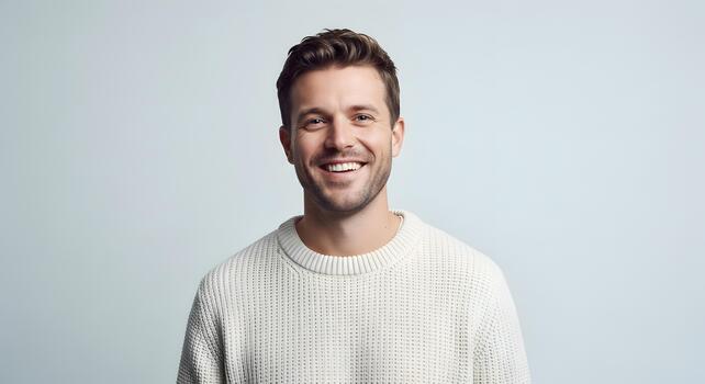 Portrait of a happy young man smiling confidently wearing a casual sweater against a plain background photo