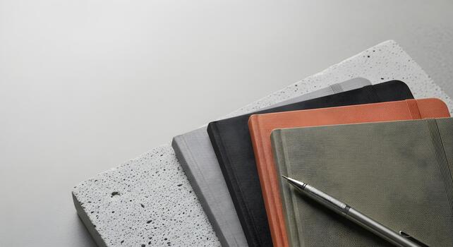Stack of Stylish Notebooks and Pen Arranged on Concrete Block for Creative Writing or Business Planning photo
