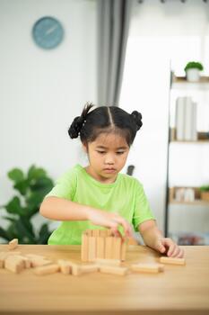 Young child engaged in creative play with wooden building blocks, focused on task, developing fine motor skills in bright indoor environment photo