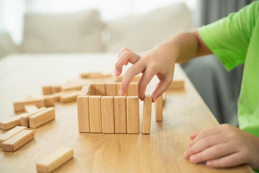 Child's hand building structure with wooden blocks on table, creativity and play, educational activity at home, early childhood development and learning experience photo