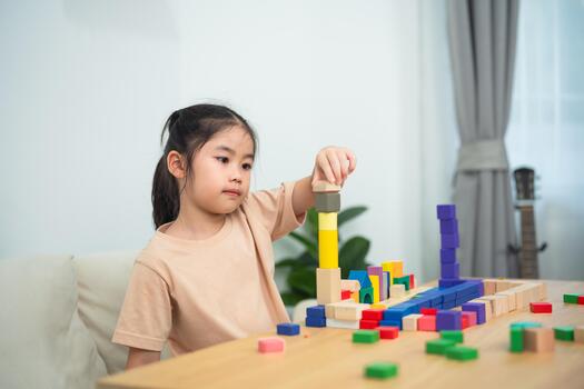 Young girl engaging in creative play with colorful building blocks, developing fine motor skills, and enhancing cognitive abilities in a bright room photo