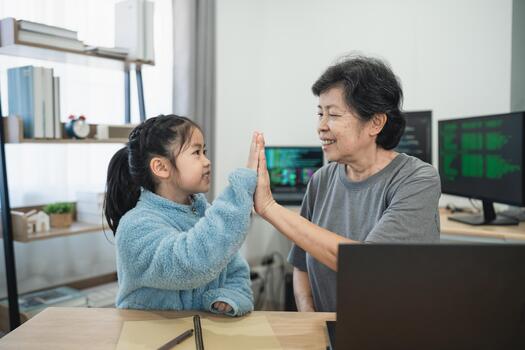 Grandmother and granddaughter enjoying playful interaction at home with technology, fostering connection and family bonding through shared activities photo