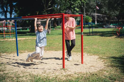 Joyful children playing at a playground, one child hanging from a monkey bar while another stands beside them in a sunny park setting, vibrant colors and active lifestyle photo