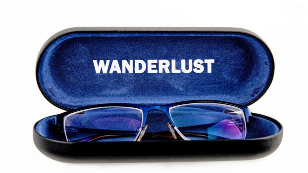 A pair of blue spectacles rest in an open case lined with blue velvet that has the word Wanderlust printed on its lining, set against a pure white backdrop, suggestive of exploration photo