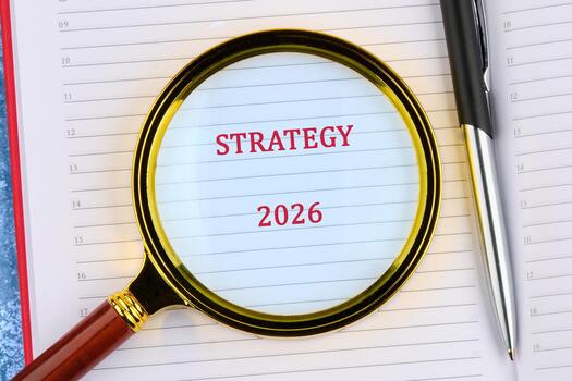 Planning for the future with strategy details for 2026, highlighted through a magnifying glass on a notepad, emphasizing careful organization and foresight photo