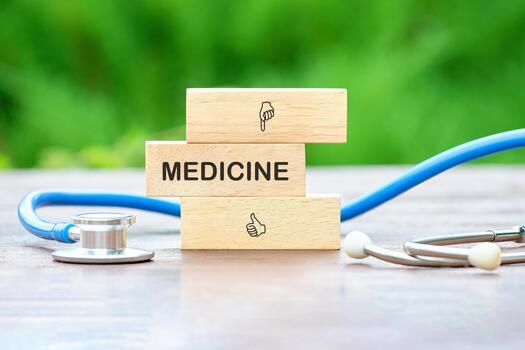 Wooden blocks spell out medicine beside a stethoscope on a rustic wooden table. The green nature backdrop emphasizes a connection to health and well-being in a calm atmosphere photo