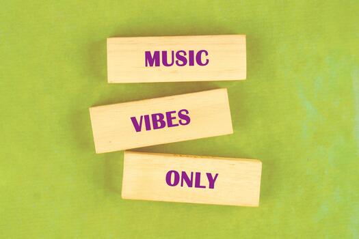 Three wooden blocks rest on a light green surface. The words MUSIC , VIBES , and ONLY are printed in purple on each of the blocks photo