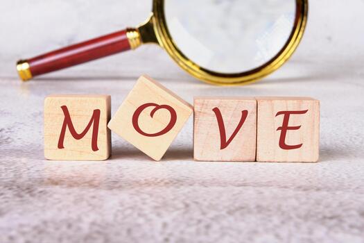 Wooden blocks spell out the word move, while a magnifying glass sits in the background. One block is tilted, creating a dynamic feel to the word photo