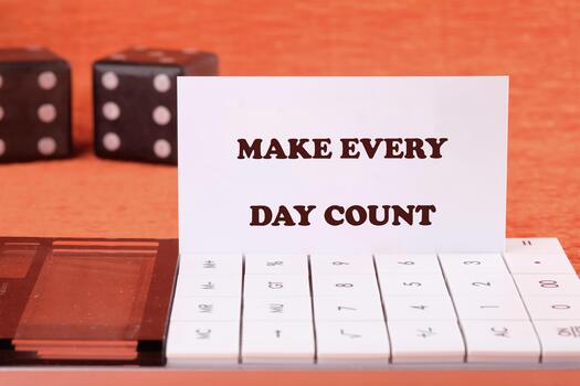 Concept words MAKE EVERY DAY COUNT on a business card with game cubes in the background and a calculator in the foreground photo