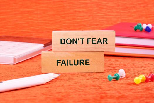 Concept text DO NOT FEAR FAILURE made of wooden blocks on an orange background with stationery lying next to it photo