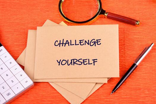Believe in yourself, overcoming challenges concept. CHALLENGE YOURSELF text written on an envelope on a bright background, along with a magnifying glass, calculator, and pen photo